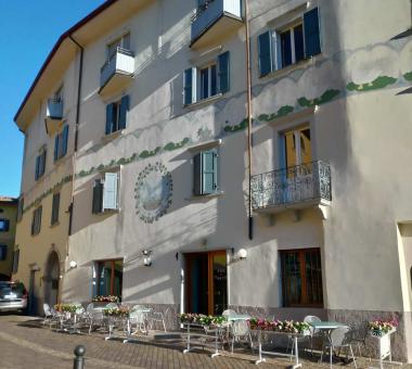 Edificio con decorazioni floreali e tavolini all'aperto su strada acciottolata.